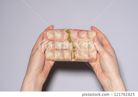 Popular white Dubai chocolate with pistachio, dried raspberry, tahini and kadaif filling, chocolate broken in woman's hands. Confectionery and handmade sweets, chocolatier Popular white Dubai chocolate with pistachio, dried raspberry, tahini and kadaif filling, chocolate broken in woman's hands. Confectionery and handmade sweets, chocolatier 121762825
