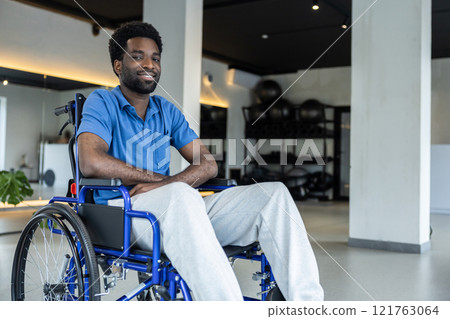 Smiling young african american man in a wheeling -chair in a clinic hall 121763064