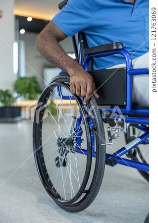 Close up of a man in blue tshirt sitting in a wheeling-chair 121763069