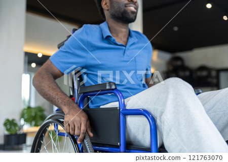 Close up of a man in blue tshirt sitting in a wheeling-chair Close up of a man in blue tshirt sitting in a wheeling-chair 121763070