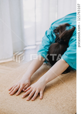 Close-up of a person stretching forward in childs pose on a cork yoga mat. Home yoga practice, mindfulness, and relaxation 121763107