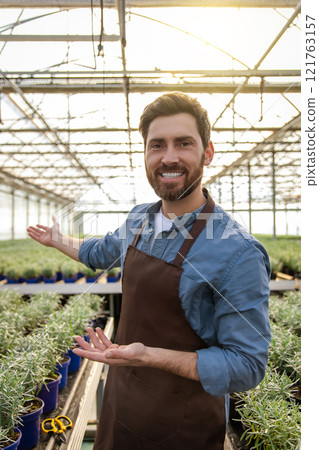 Positive bearded young man in a greenhouse looking determined 121763157
