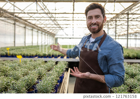 Positive bearded young man in a greenhouse looking determined 121763158