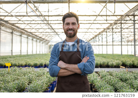 Positive bearded young man in a greenhouse looking determined 121763159