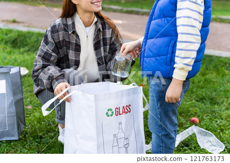Woman volunteer and boy cleaning garbage together in social project Woman volunteer and boy cleaning garbage together in social project 121763173