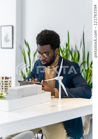 African american architect looking focused while scrutinizing the new mock up of a living building African american architect looking focused while scrutinizing the new mock up of a living building 121763394