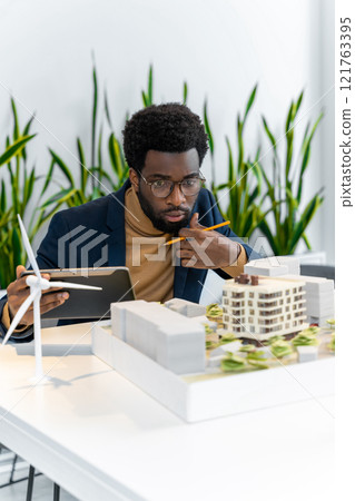 African american architect looking focused while scrutinizing the new mock up of a living building African american architect looking focused while scrutinizing the new mock up of a living building 121763395