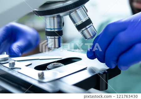 Medical man working in lab using microscope for analysis of virus testing and vaccine 121763430