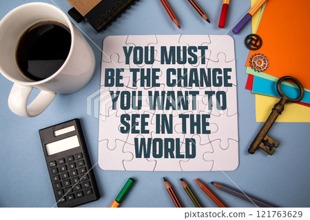 You Must Be The Change You Want To See In The World. White puzzle and office supplies on table You Must Be The Change You Want To See In The World. White puzzle and office supplies on table 121763629