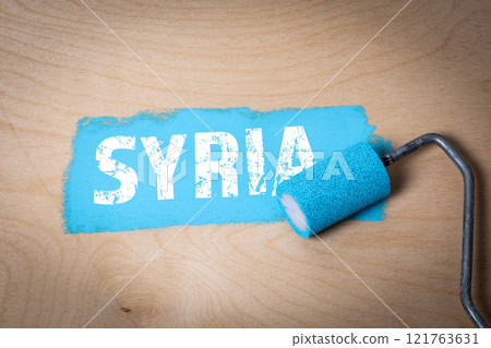 Syria. Text and blue paint with a paint roller on a wooden texture background 121763631