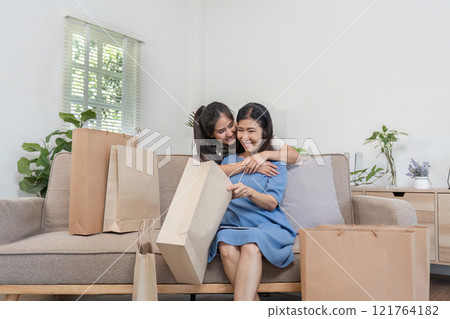 Joyful Mother and Child Bonding Over Shopping with Paper Bags in Cozy Home Setting Joyful Mother and Child Bonding Over Shopping with Paper Bags in Cozy Home Setting 121764182