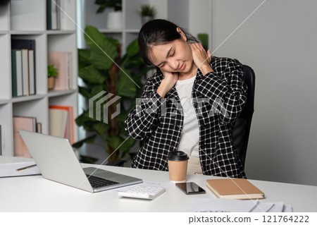 Exhausted Businesswoman at Desk with Laptop and Coffee in Modern Office Setting 121764222