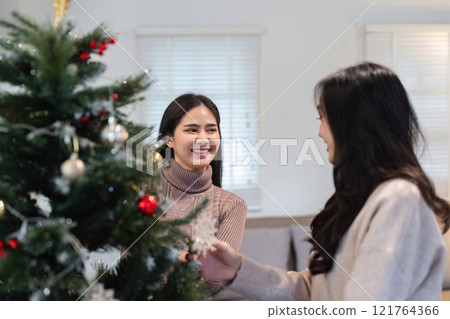 Young Woman Joyfully Decorating Her Room for a Cozy and Festive Christmas Celebration Young Woman Joyfully Decorating Her Room for a Cozy and Festive Christmas Celebration 121764366
