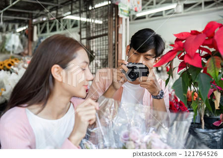 Romantic couple captures valentine's moments at flower market engaging with nature close-up emotional connection 121764526
