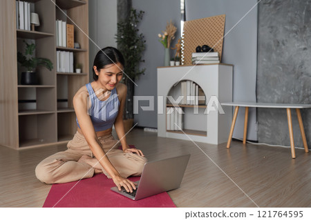 Young Healthy Woman Practicing Yoga at Home in a Modern Living Room Setting for Relaxation and Wellness 121764595