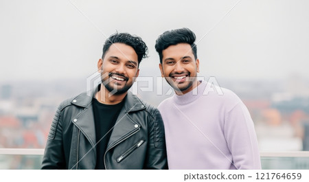 Two young south asian males smiling outdoors with urban skyline in background Two young south asian males smiling outdoors with urban skyline in background 121764659