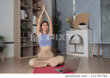 Young Healthy Woman Practicing Yoga at Home in a Modern Living Room Setting with Natural Light and Minimalist Decor Young Healthy Woman Practicing Yoga at Home in a Modern Living Room Setting with Natural Light and Minimalist Decor 121764768