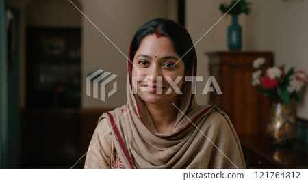 Smiling south asian woman in traditional attire indoors 121764812