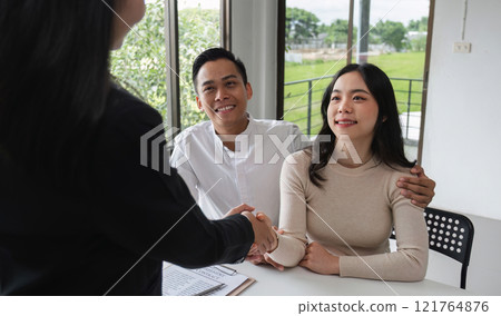 Happy Couple Signing Real Estate Sales Contract with Agent in Modern Office Setting Happy Couple Signing Real Estate Sales Contract with Agent in Modern Office Setting 121764876