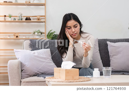 Feeling sick and unwell woman at home taking temperature indoor living room personal health casual setting close-up view Feeling sick and unwell woman at home taking temperature indoor living room personal health casual setting close-up view 121764930