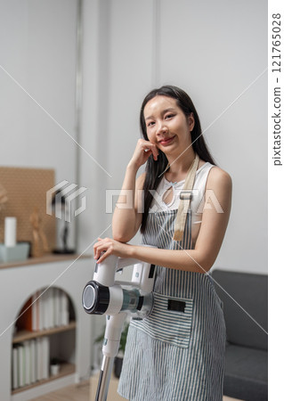 Young Woman Joyfully Cleaning Modern Home with Vacuum Cleaner in Bright and Stylish Living Room Setting Young Woman Joyfully Cleaning Modern Home with Vacuum Cleaner in Bright and Stylish Living Room Setting 121765028