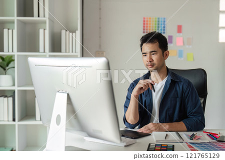 Creative Graphic Designer Working in Modern Design Studio with Digital Tools and Color Samples for Innovative Projects 121765129