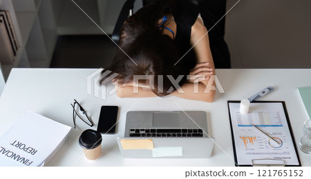 Exhausted Young Businesswoman Overwhelmed by Work Stress at Office Desk with Laptop and Documents Exhausted Young Businesswoman Overwhelmed by Work Stress at Office Desk with Laptop and Documents 121765152