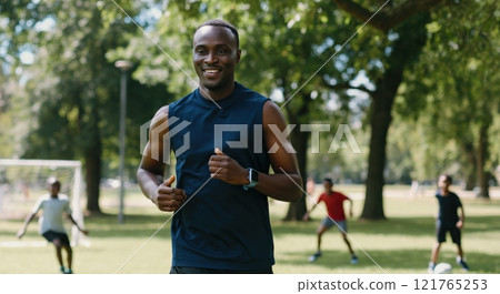 African male runner exercising in park with others, fitness team outdoors concept 121765253