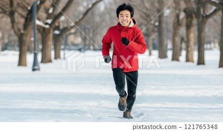 Asian teen boy running in winter park with snow-covered trees Asian teen boy running in winter park with snow-covered trees 121765348