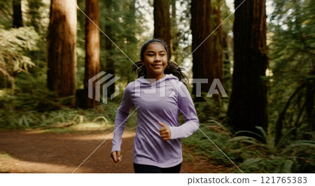 Young asian female jogging in forested park promoting active lifestyle 121765383