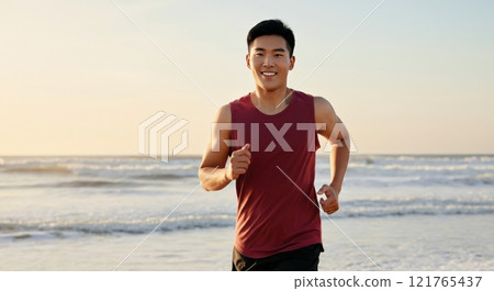 Young asian male jogging on beach at sunrise for fitness and wellbeing 121765437