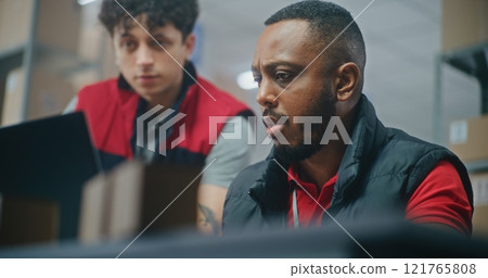 Male warehouse associate brings parcel to African American logistics specialist 121765808
