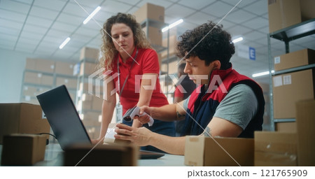 Two logistics specialists scan parcel with scanner, check information on laptop 121765909