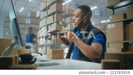 African American warehouse clerk scans parcels using tablet computer, works in post office African American warehouse clerk scans parcels using tablet computer, works in post office 121765919