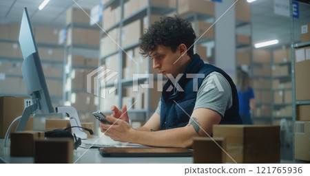 Logistics manager scans small parcels using smartphone, works in warehouse of post office 121765936