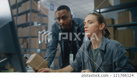 Female logistics coordinator works on computer. Warehouse associate scans code on parcel 121766124