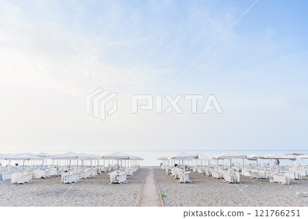 Idyllic scene of deck chairs under an umbrella on a clean beach in the hot afternoon sun. Idyllic scene of deck chairs under an umbrella on a clean beach in the hot afternoon sun. 121766251