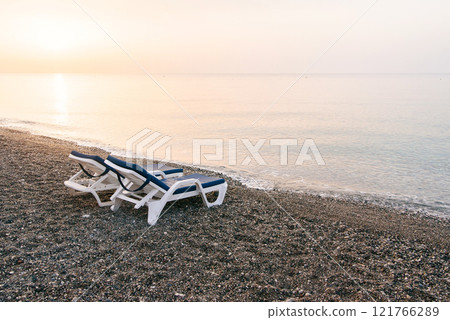 Two plastic sun beds on the sea beach at sunrise. Summer vacation concept. 121766289
