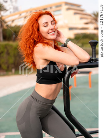 Relaxed happy woman leaning on exercise equipment Relaxed happy woman leaning on exercise equipment 121767119