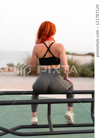 Sensuous jogger woman sitting on railing at beach Sensuous jogger woman sitting on railing at beach 121767120
