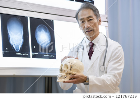一位男醫生拿著頭骨模型並解釋 121767219