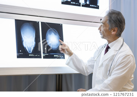A doctor explaining while looking at an X-ray of the head 121767231