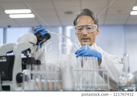 一位身穿白大褂的老人用顯微鏡工作 121767432