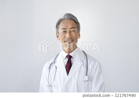A male doctor in his 60s wearing a white coat and looking at the camera 121767490