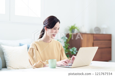Housewife using a computer in the living room, working from home image 121767554
