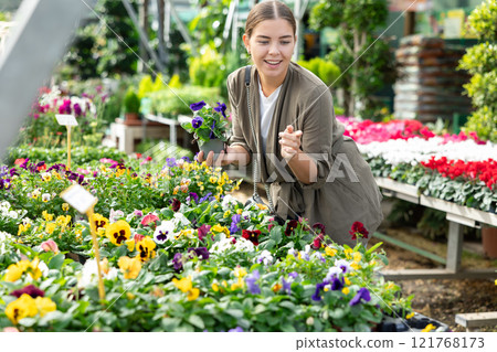 Happy female customer chooses viola wittrockiana flower in flower shop Happy female customer chooses viola wittrockiana flower in flower shop 121768173