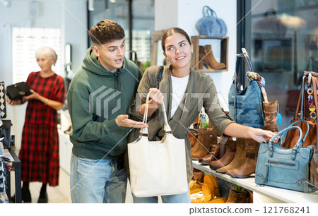 Couple man and woman choosing handbag in store 121768241