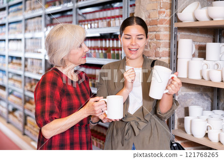 Two women choose mugs or cups together in pottery and ceramics shop Two women choose mugs or cups together in pottery and ceramics shop 121768265