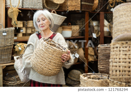 Female designer choosing decorative handmade wickerwork for interior in store Female designer choosing decorative handmade wickerwork for interior in store 121768294