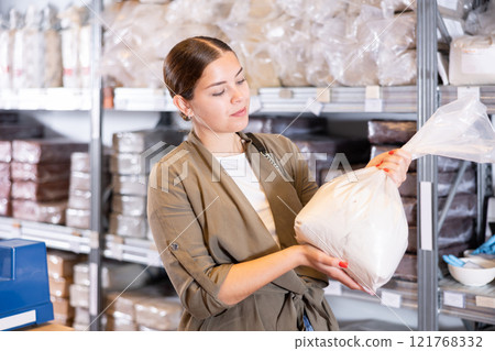 Young woman chooses pottery clay in shop Young woman chooses pottery clay in shop 121768332
